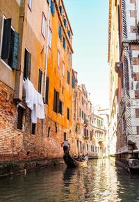 People on canal by buildings in city
