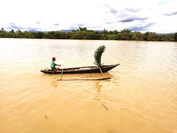 Man in boat on lake against sky