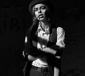 Portrait of young woman smoking cigarette against wall