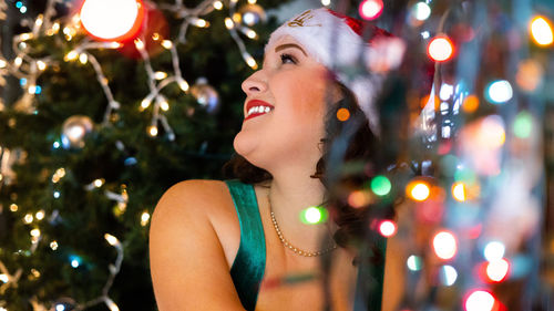 Young woman looking away against christmas tree