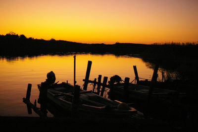 Silhouette boats in lake against orange sky