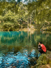 Man sitting by lake in forest