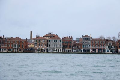 Buildings by sea against clear sky