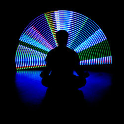 Rear view of silhouette person in illuminated amusement park