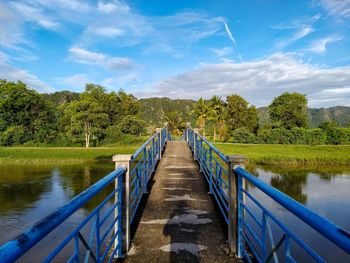 Footbridge over lake against sky