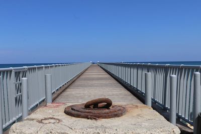 Rusty metal by sea against clear sky