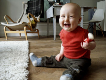 Happy baby boy sitting on floor at home