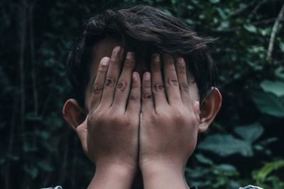 Close-up portrait of a boy covering face