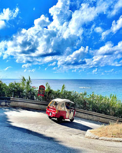 Car on road by sea against sky