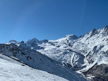 Scenic view of snowcapped mountains against clear blue sky