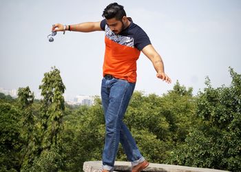 Young man balancing on retaining wall against trees