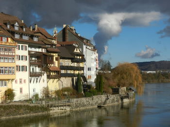 Buildings by river against sky