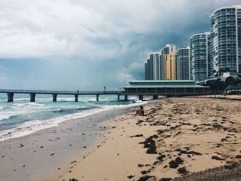 Scenic view of beach by city against sky