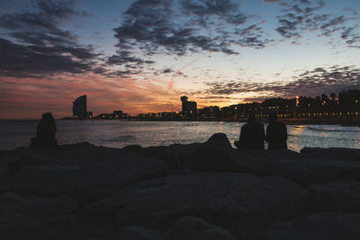 Rear view of woman looking at sea against sky during sunset