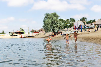 People by boats in sea against sky