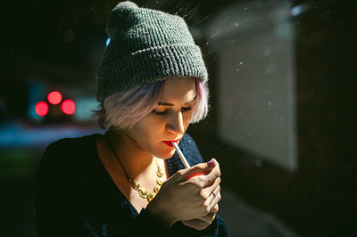 Close-up of young woman lighting cigarette