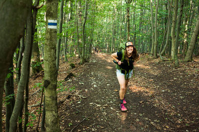 Woman standing by tree trunks in forest
