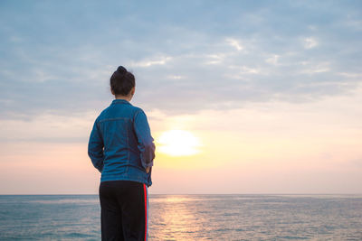 Rear view of man looking at sea against sky