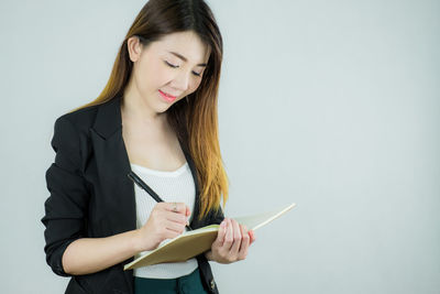 Beautiful young woman wearing mask against white background