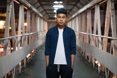 Portrait of young man standing against railing