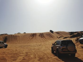 Car on desert land against clear sky