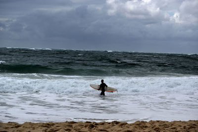 Man surfing in sea against sky