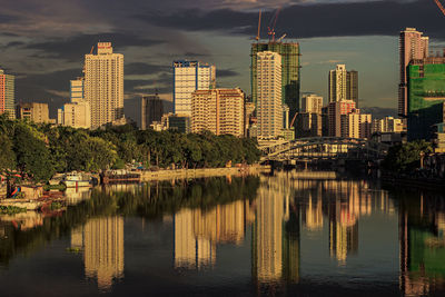 Buildings by river against sky in city