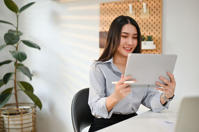 Portrait of young woman using laptop at home