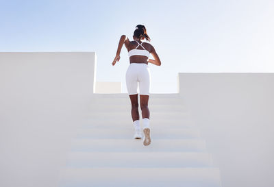 Full length of woman jumping against white background