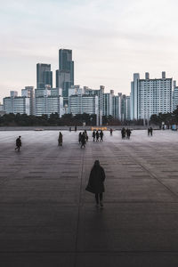 Young woman in black coat walks on the street in metropolis. skyscrapers on the background. 