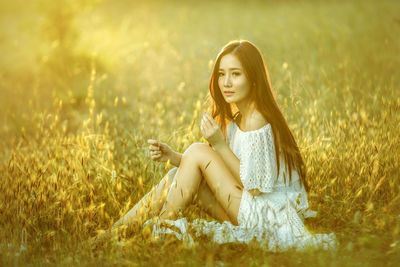 Portrait of young woman sitting on field