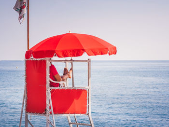 Red man sitting in sea against clear sky