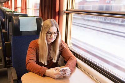 Young woman using cell phone in train