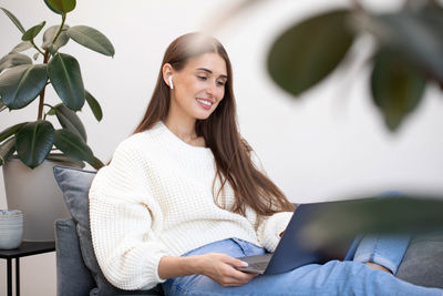 Young woman sitting on sofa at home