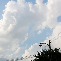 Low angle view of power lines against cloudy sky
