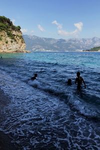 Men swimming in sea against sky