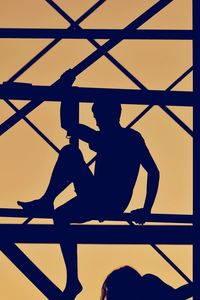Silhouette men sitting against sky during sunset