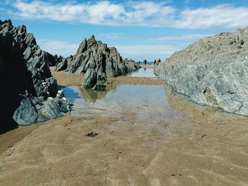 Rock formations on beach against sky