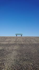 Bench on landscape against clear sky