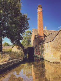 Old building by canal against clear sky