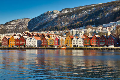 Houses by lake and mountains against sky in town