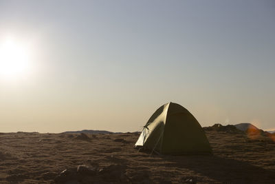 Tent on rock against sky during sunset