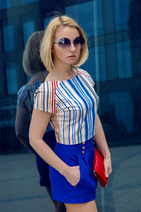 Young business woman in short blue trunks standing and waiting the bank of glass , high building