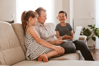 Vido call. dad and children sit on the couch and call online grandparents or mom. communication
