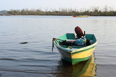 Boy sitting on boat moored in lake against sky