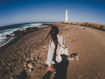 Rear view of woman standing by sea against clear sky