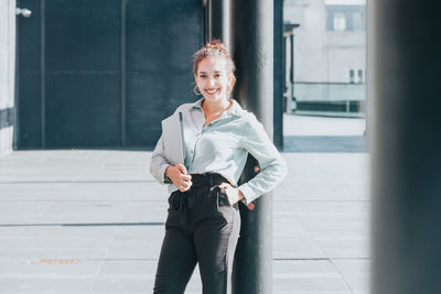 Portrait of young woman standing in city