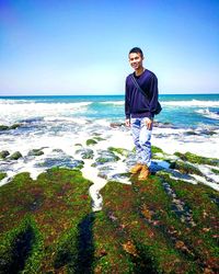 Portrait of smiling man standing on beach against clear sky