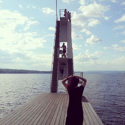 Man standing on pier by sea against sky