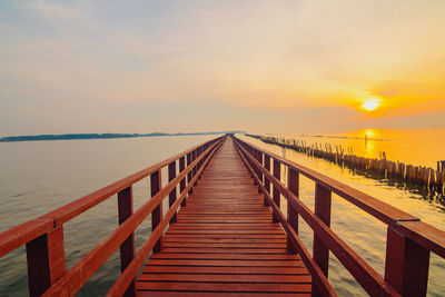 Pier over sea against sky during sunset